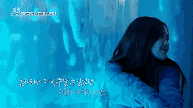 a woman is hugging herself in front of a blue background .