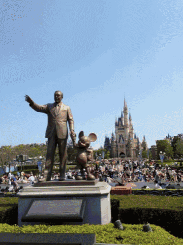 a statue of walt disney and mickey mouse in front of a crowd