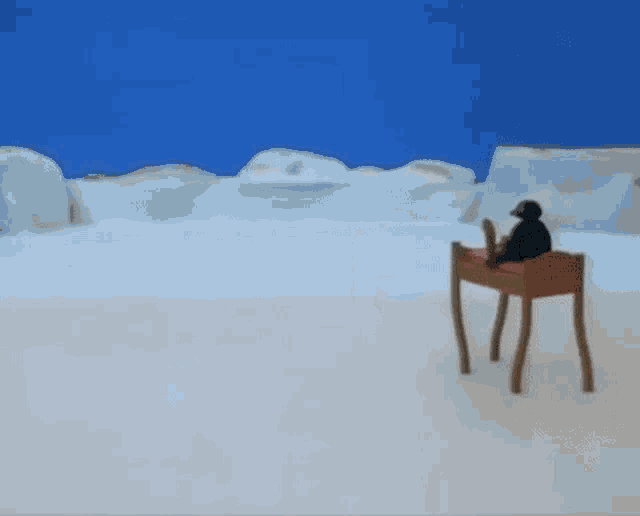 a penguin is sitting on top of a wooden table in the snow .
