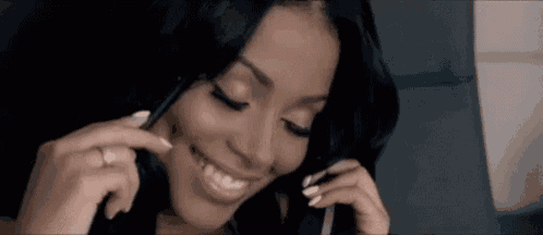 a woman is smiling while talking on a cell phone and wearing a ring .