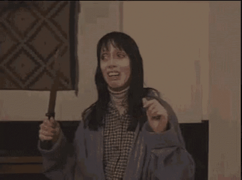 a woman is holding a knife in her hand in a dark room .