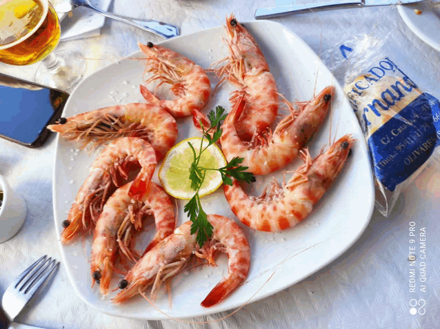 a white plate topped with shrimp and a lemon slice next to a bag of picado grand