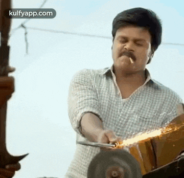 a man with a mustache is smoking a cigarette while using a grinder to cut a piece of metal .