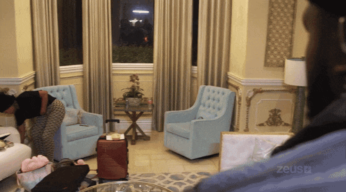 a room with blue chairs and a red suitcase that says zeustv on the bottom