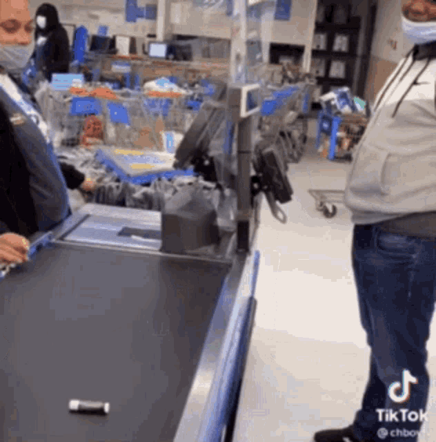a man wearing a mask is standing next to a cash register in a store .