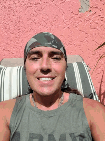 a man wearing a headband and a grey tank top with the word day on it