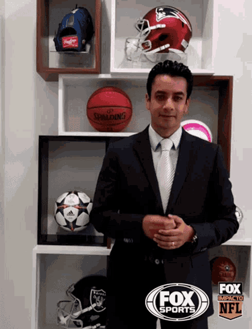 a man in a suit and tie is standing in front of a display of nfl helmets