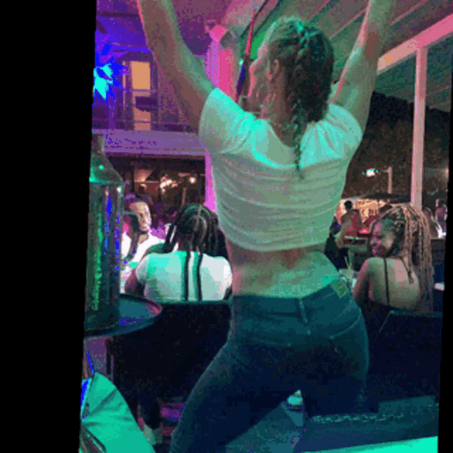 a woman in a white shirt is dancing in a crowded room