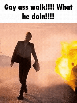 a man in a suit is walking in front of a fire with the caption gay ass walk !!! what he doin !!!