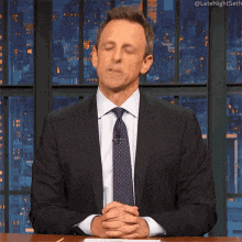 a man in a suit and tie with his hands folded