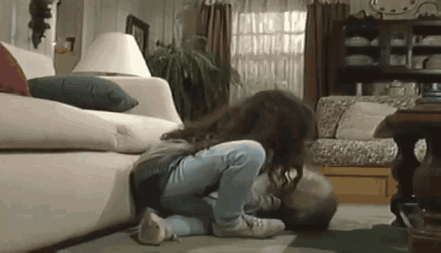 a little girl is kneeling on the floor in front of a couch .