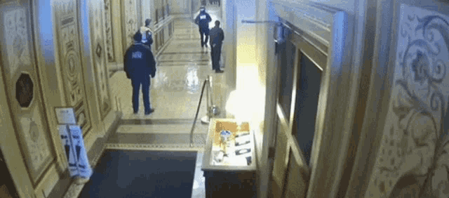 a group of men are walking down a hallway and one of them is wearing a jacket that says ' ncr '