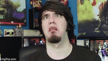 a man with a beard is making a funny face while sitting in front of a computer