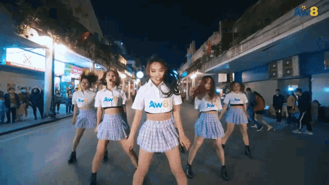 a group of women wearing aw8 shirts are dancing