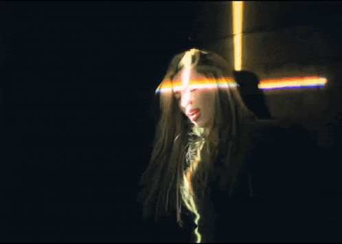 a woman in a dark room with a rainbow of light coming out of her hair