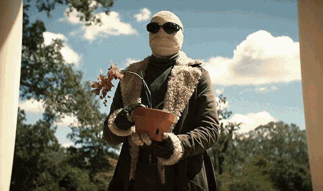 a man with a bandage on his face holds a potted plant