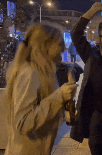 a woman in a ponytail is holding a bottle in her hand