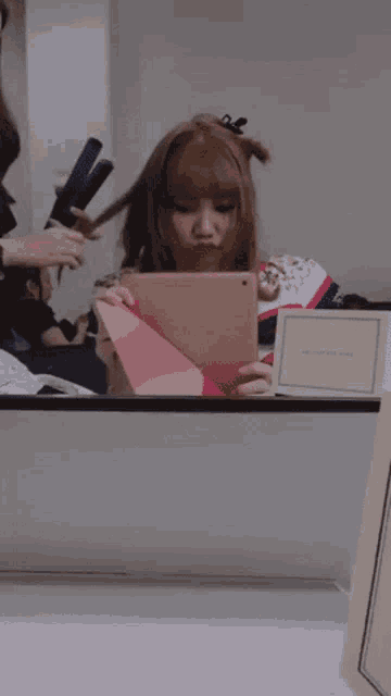 a woman looking at a tablet in front of a mirror with a card that says welcome card