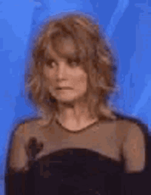 a woman in a black dress is standing in front of a blue background .