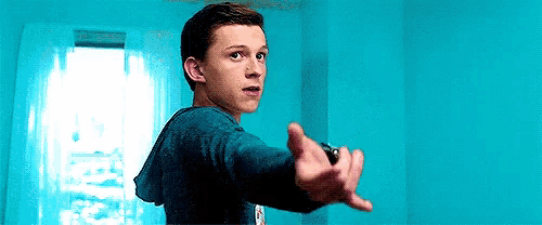 a young man in a blue shirt is holding a remote control in his hand in a blue room .