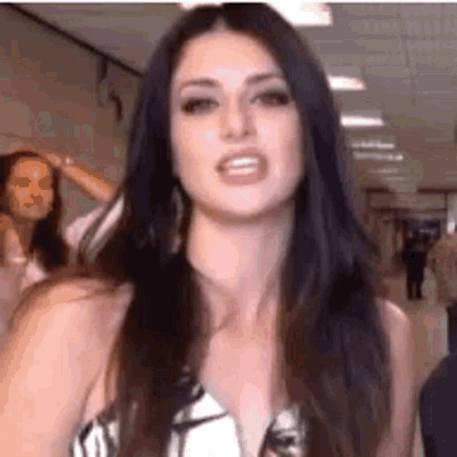 a woman with long dark hair is making a funny face .