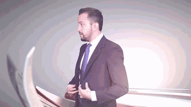 a man in a suit and tie is standing in front of a gray background