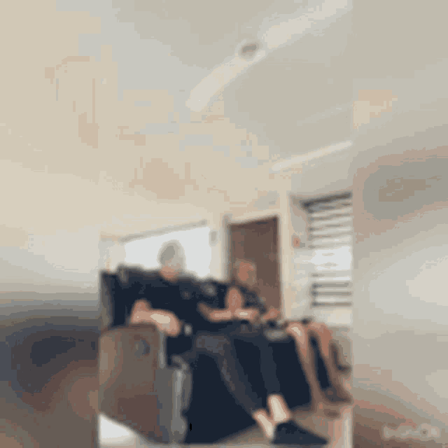 a blurry picture of two people sitting on a couch in a living room