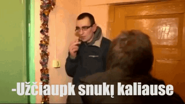 a man smoking a cigarette next to a sign that says - uzciaupk snuki kaliause