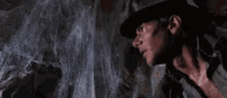 a man in a hat is looking at a book in a cave .