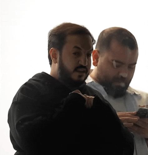 a man with a beard is looking at a cell phone