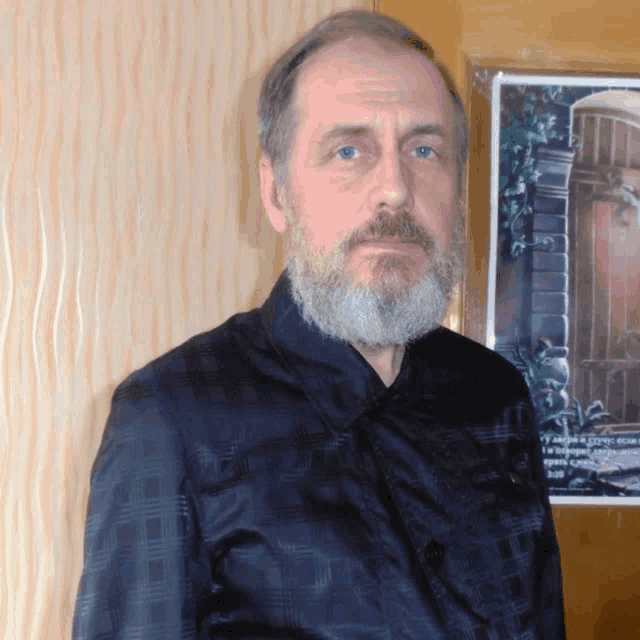 a man with a beard and a black shirt stands in front of a poster that says ' y ' on it