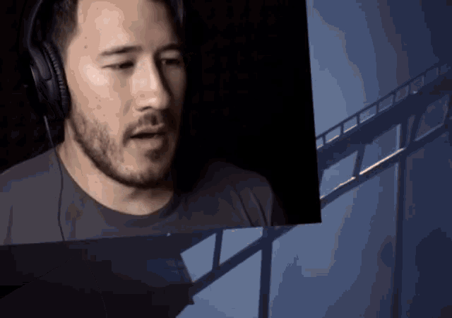 a man with a beard wearing headphones looks at a picture of a roller coaster