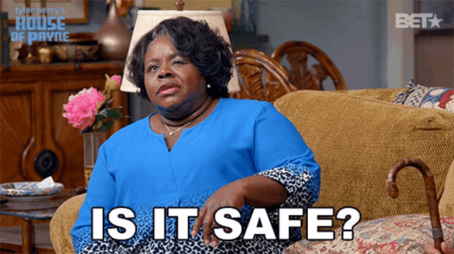a woman in a blue shirt is sitting on a couch with the words is it safe below her