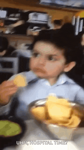 a young boy is eating tortilla chips at a restaurant .