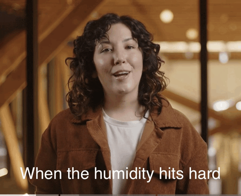 a woman says when the humidity hits hard while wearing a brown jacket