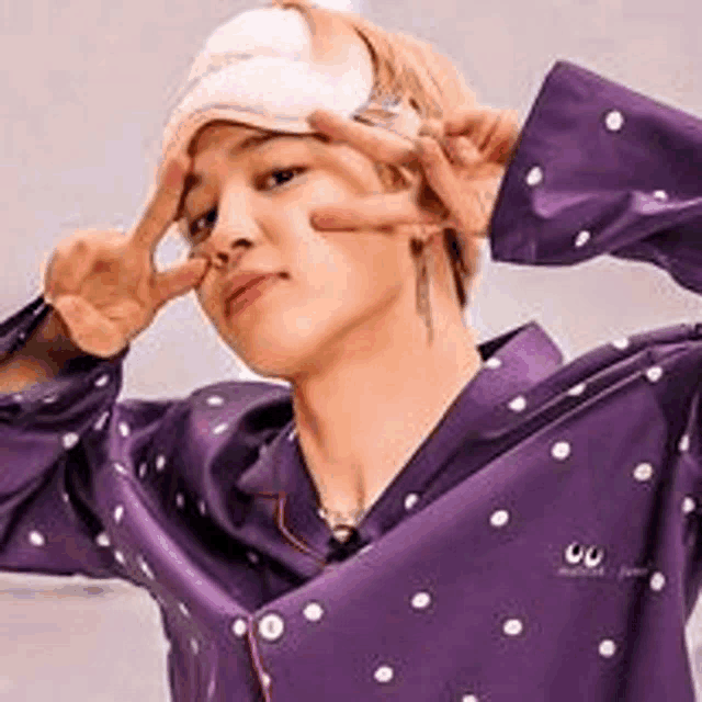 a young man wearing a purple pajama shirt and a sleep mask on his head .