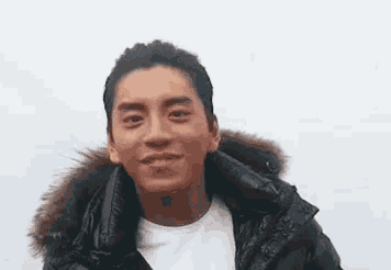 a man wearing a black jacket with a fur hood is smiling for the camera .