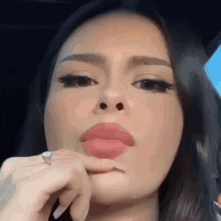 a woman with a ring on her finger is making a funny face with her finger in her mouth .