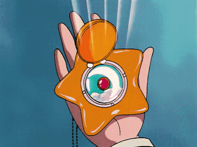 a hand is holding a star shaped object with a ruby in the middle