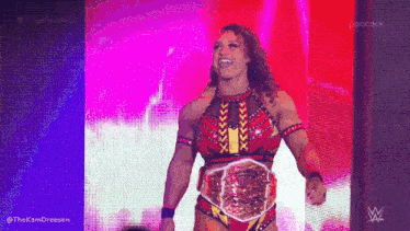 a female wrestler is standing on a stage wearing a championship belt .