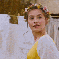 a woman with a flower crown on her head is wearing a yellow dress .