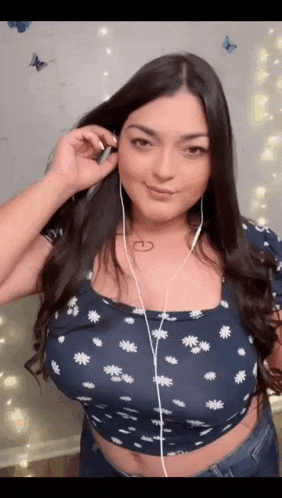 a woman wearing headphones and a crop top is smiling and looking at the camera .