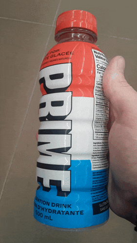 a person is holding a bottle of prime hydration drink in their hand