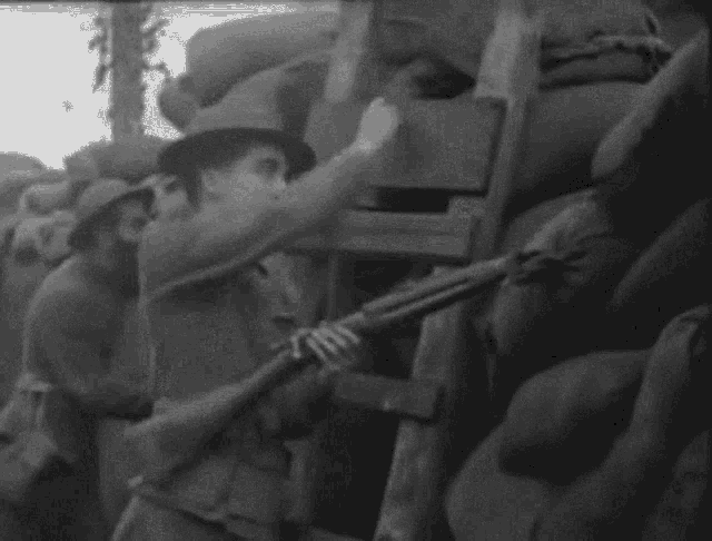 a soldier is holding a gun in a trench .
