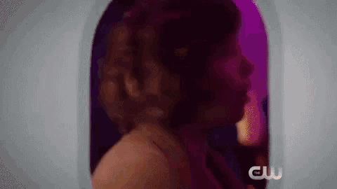 a woman in a dress is standing in front of a window with a purple light behind her .