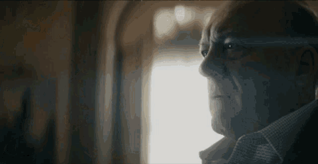 a close up of an older man 's face looking out a window .