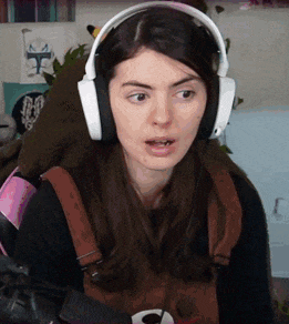 a woman wearing headphones is sitting in a chair and making a funny face .