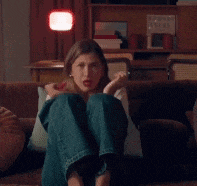 a woman is sitting on a couch with her legs crossed and a lamp behind her .