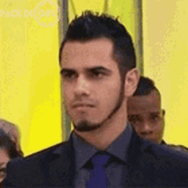 a man in a suit and tie is standing in front of a yellow background .