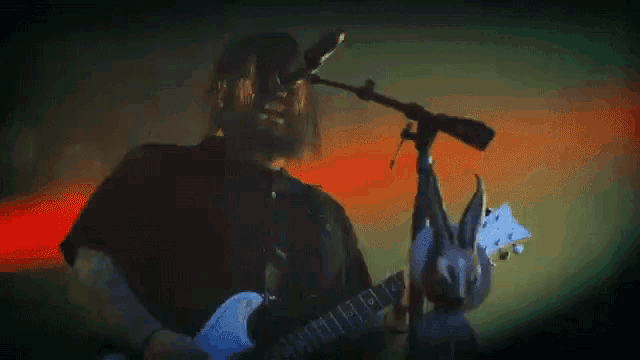 a man playing a guitar and singing into a microphone .